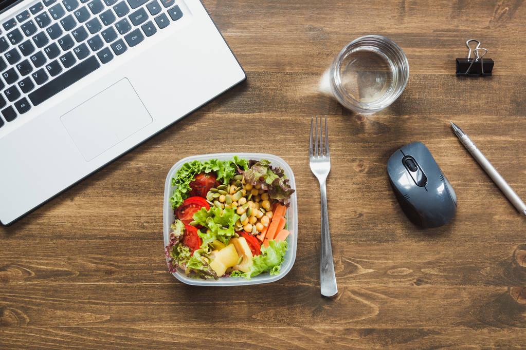 Gesundes Geschäftsessen im Büro, Salat, Wasser auf dem Holztisch. Konzept gesunde Ernährung. Lunchbox. - Foto, Bild