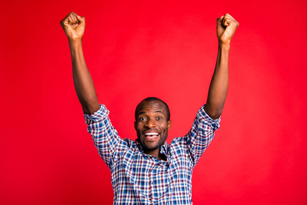 Портрет гарного красивого веселого веселого позитивного оптимістичного модного хлопця в картатій сорочці, що показує прорив жест підняття рук кулаками вгору ізольовано на яскравому яскравому блискучому червоному тлі
 - Фото, зображення