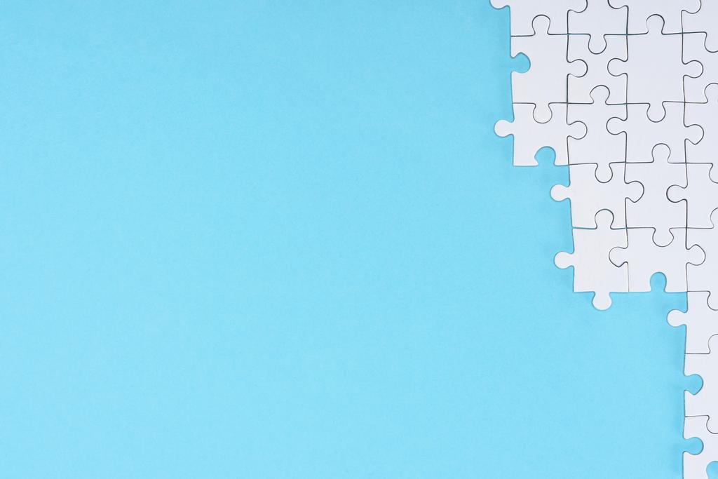 düz lay mavi zemin üzerine beyaz puzzle parçaları ile - Fotoğraf, Görsel