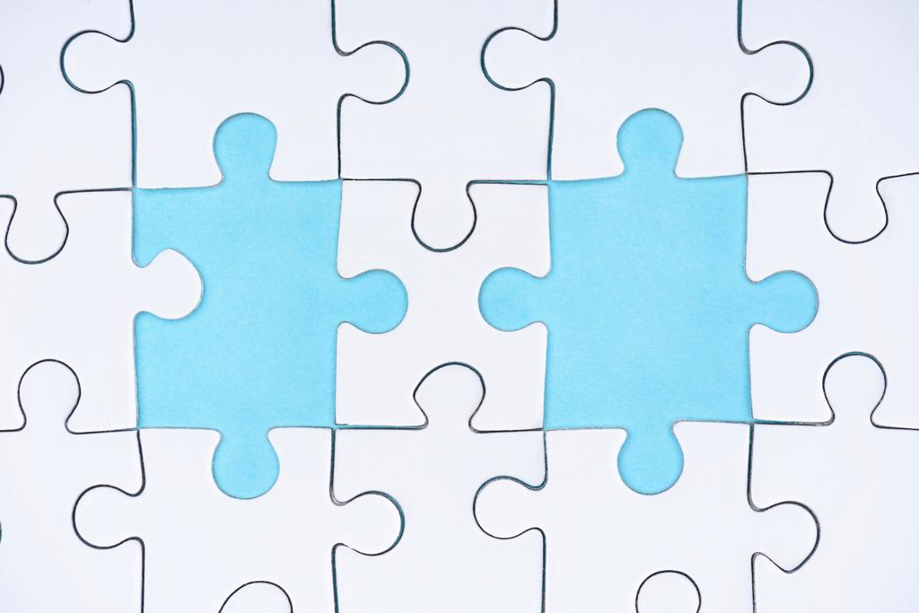 vlakke leggen met witte puzzelstukjes op blauwe achtergrond - Foto, afbeelding