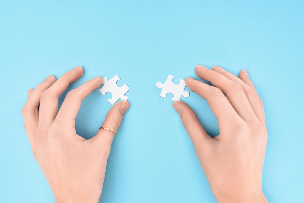 vista parziale della donna che tiene pezzi di puzzle bianchi su sfondo blu
 - Foto, immagini