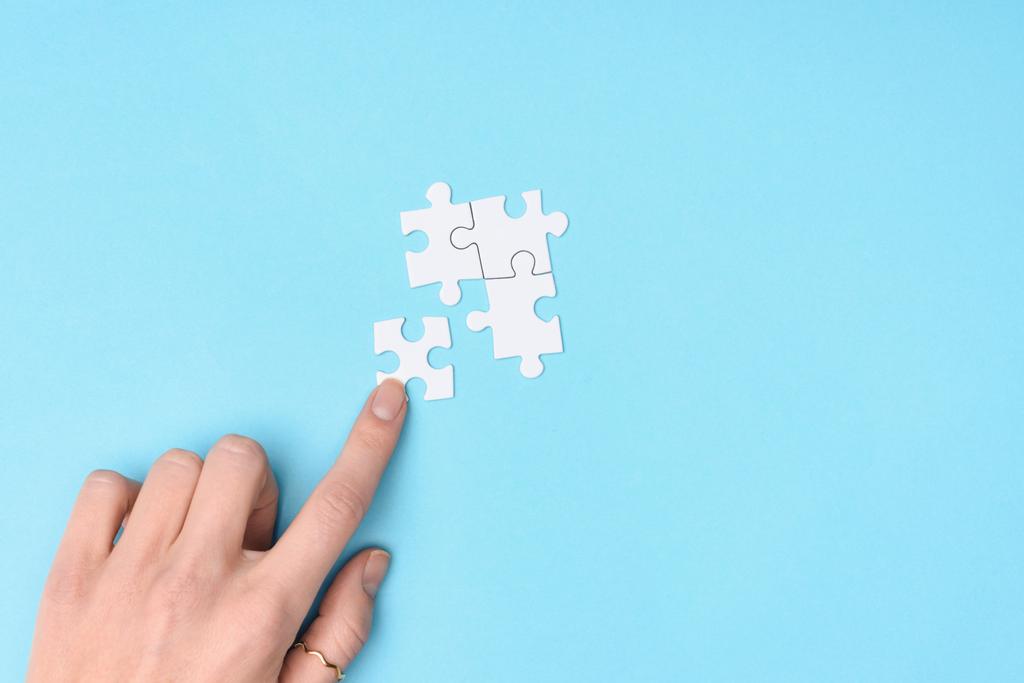 cropped shot of woman and white puzzles pieces on blue background - Photo, Image