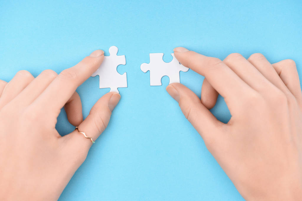 cropped shot of woman holding white puzzles pieces on blue background - Photo, Image