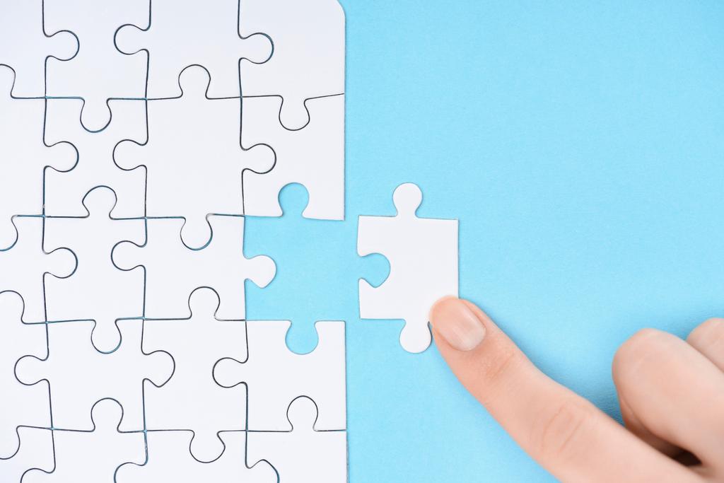 partial view of woman pointing at white puzzles pieces on blue background - Photo, Image