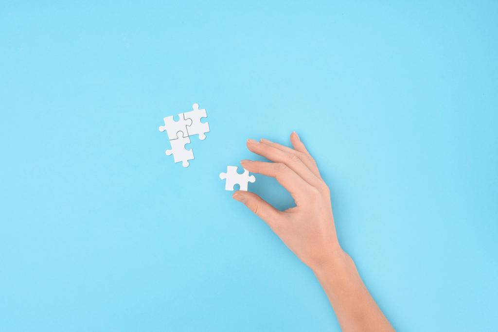 partial view of woman with white puzzles pieces on blue background - Photo, Image
