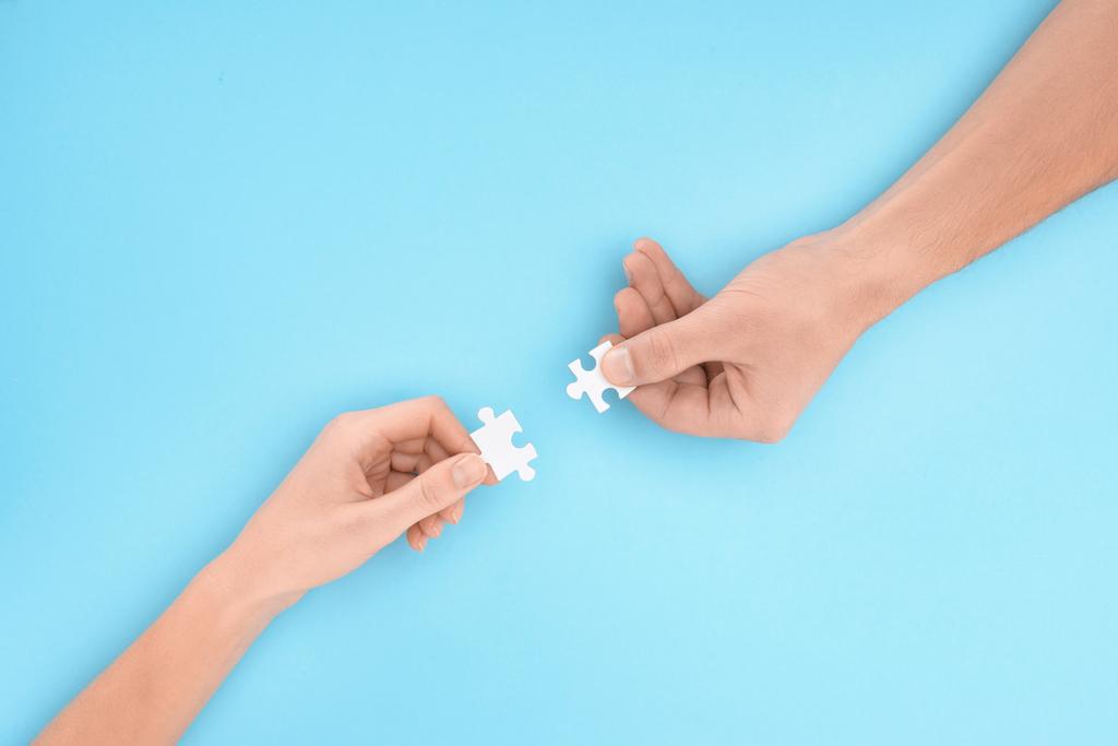 cropped shot of man and woman with white puzzle pieces on blue backdrop, cooperation concept - Photo, Image
