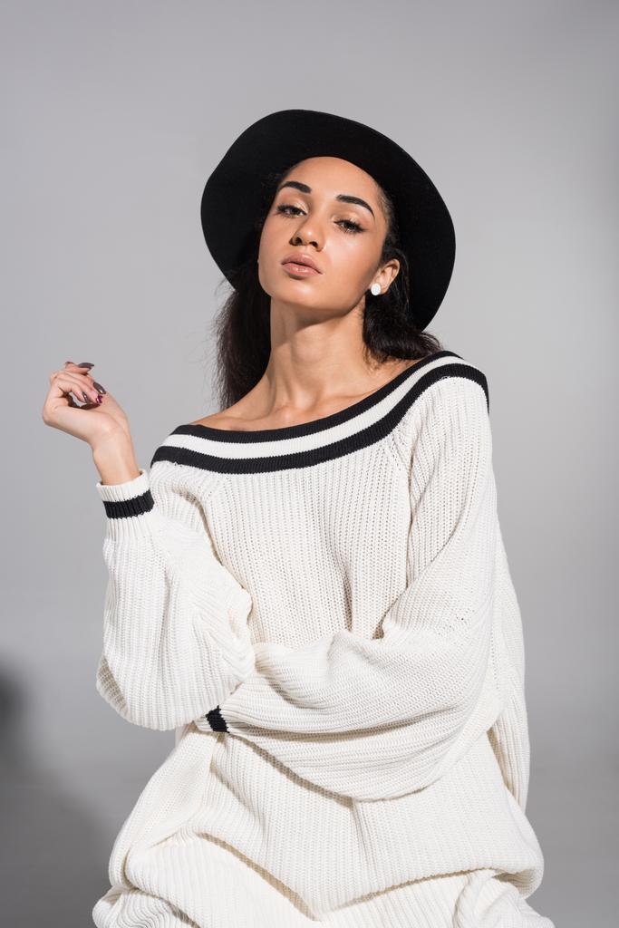 atractiva mujer joven afroamericana en ropa blanca con estilo y sombrero mirando a la cámara en blanco
 - Foto, Imagen