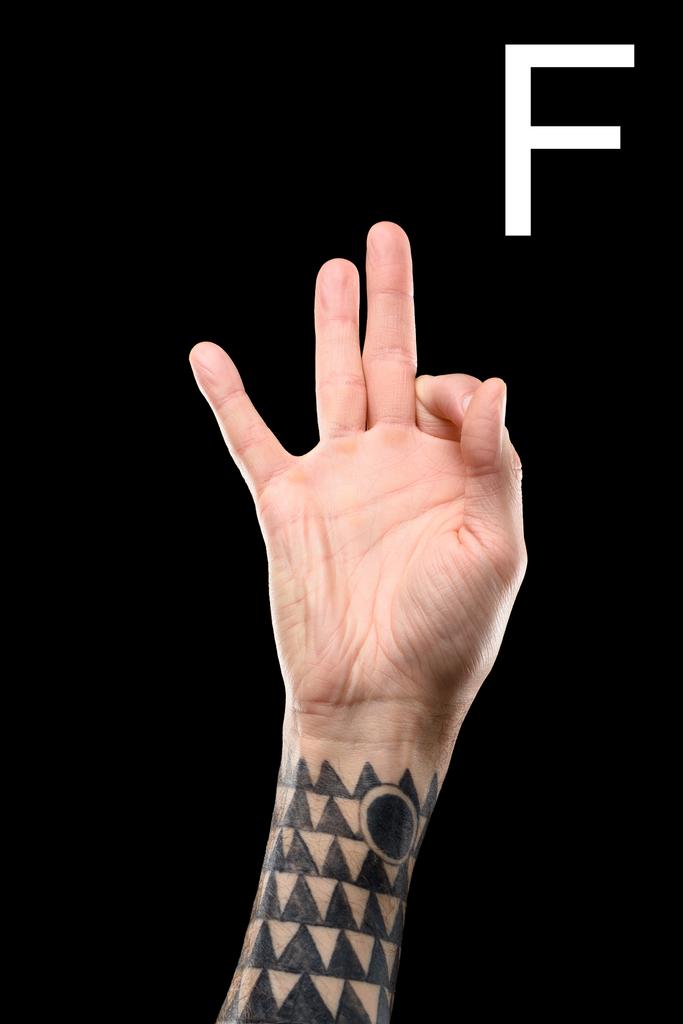 tattooed male hand showing latin letter - F, sign language, isolated on black - Photo, Image