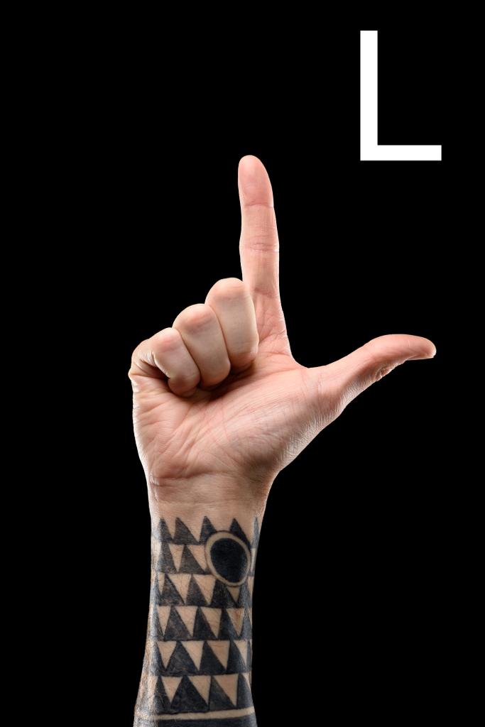 обрізаний вид татуйованої руки, що показує латинську літеру - L, мова жестів, ізольовано на чорному
 - Фото, зображення