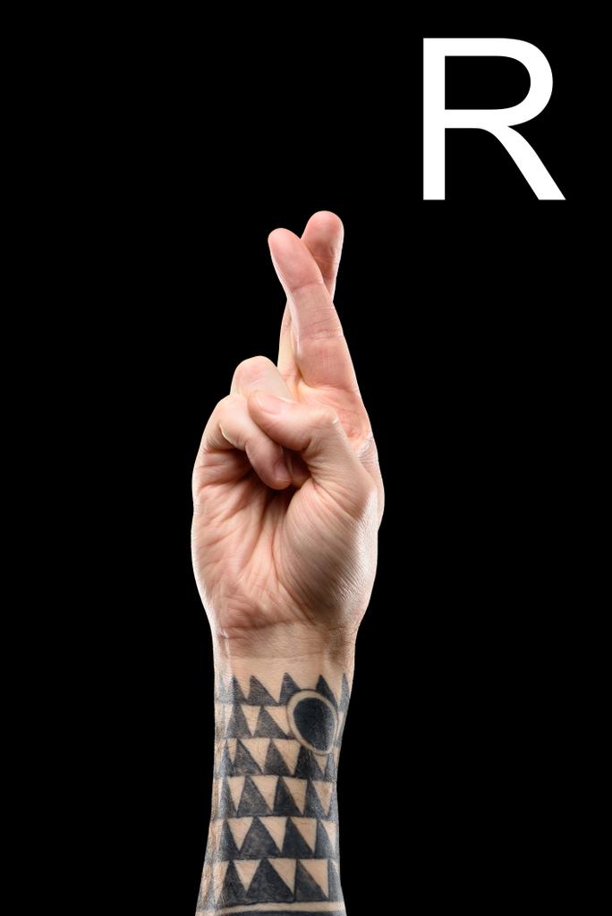 vista recortada de la mano masculina tatuada que muestra la letra latina - R, lenguaje sordo y mudo, aislado en negro
 - Foto, imagen
