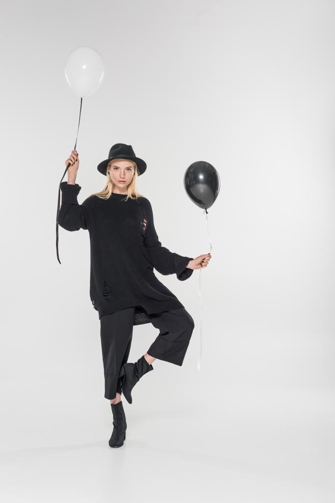 beautiful caucasian blonde woman in black clothes and hat posing with two balloons on white - Photo, Image