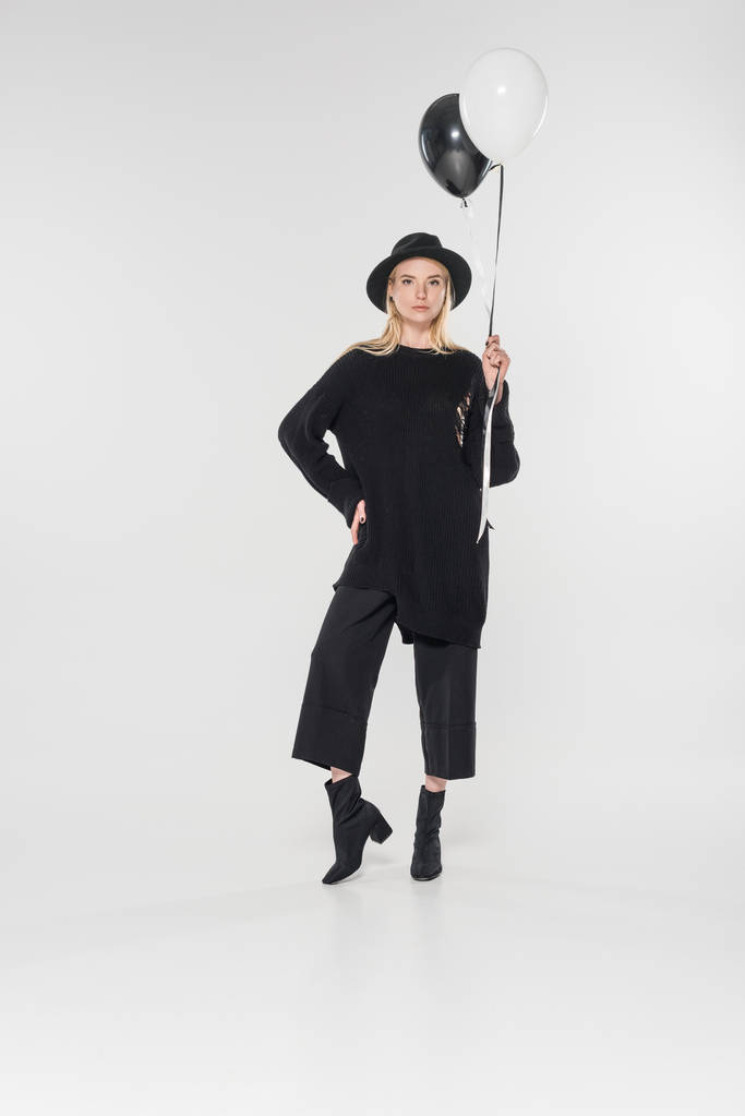 beautiful caucasian blonde woman in black clothes and hat holding balloons with helium on white - Photo, Image