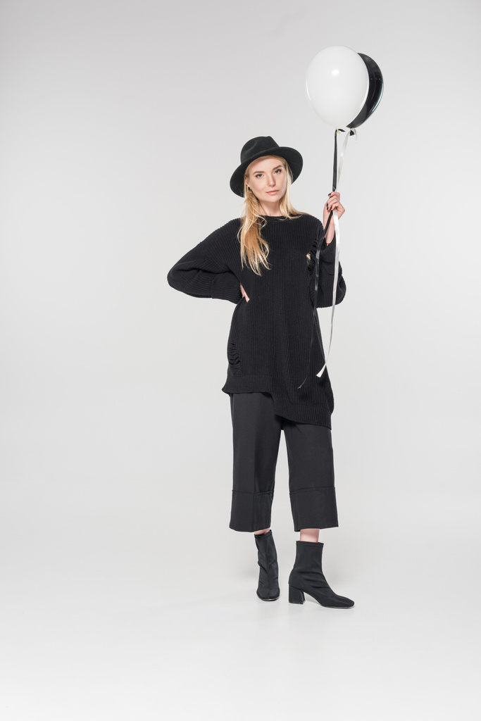 beautiful caucasian blonde woman in black clothes and hat holding two balloons with helium on white - Photo, Image