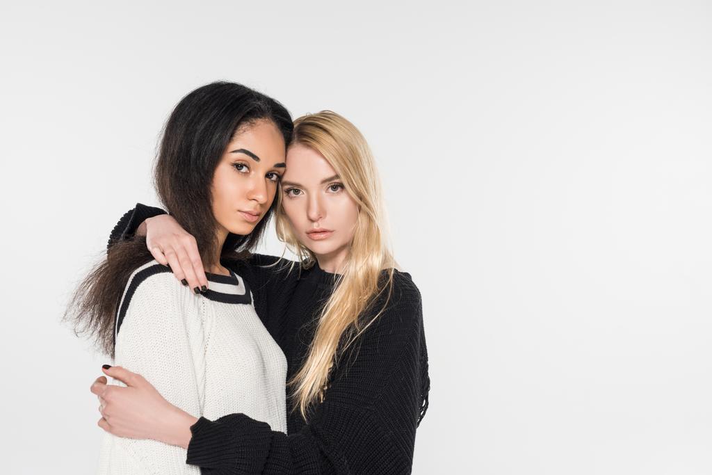kaunis monikulttuurinen lesbo pari mustavalkoisissa vaatteissa halaamalla ja katsomalla kameraa, joka on eristetty valkoisella
 - Valokuva, kuva