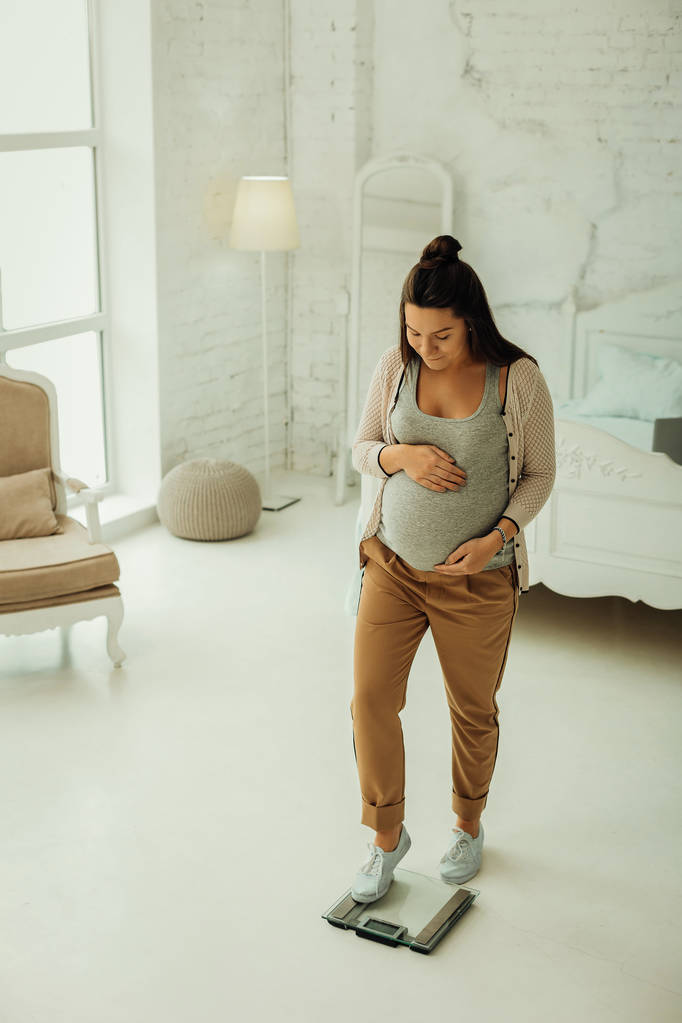 Mosolygó terhes nő súlya minden nap otthon - Fotó, kép