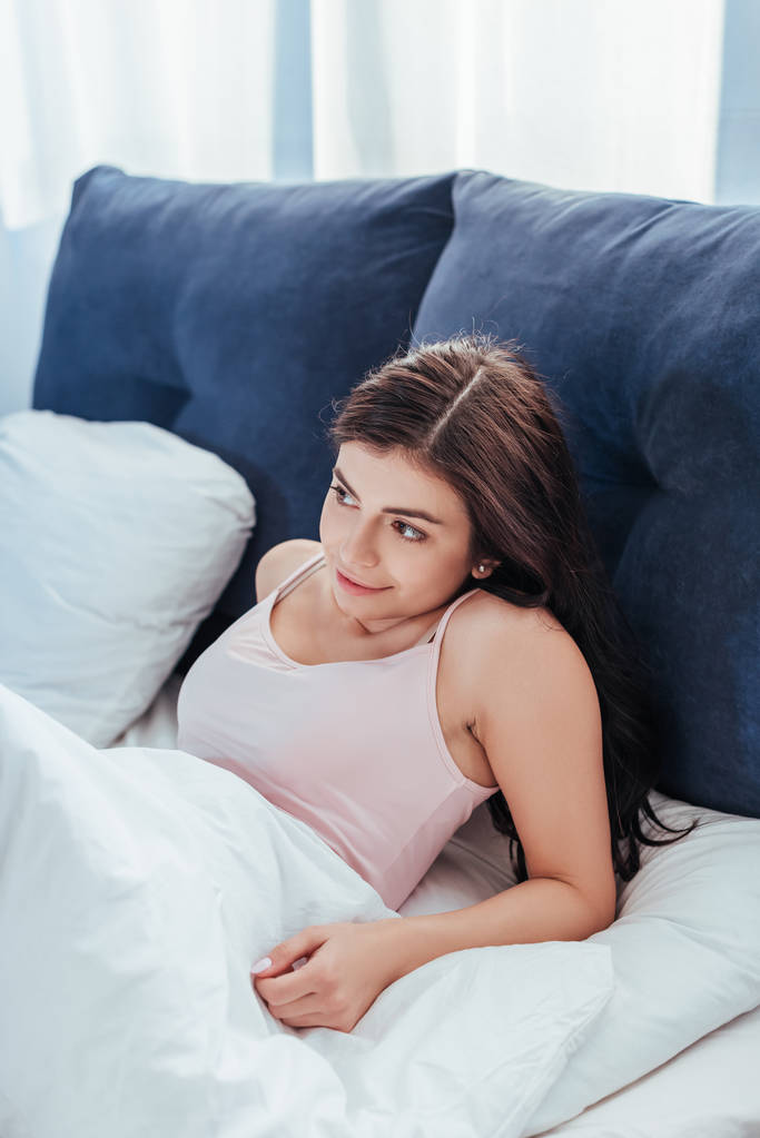 улыбающаяся девушка просыпается на кровати в утреннее время дома
 - Фото, изображение