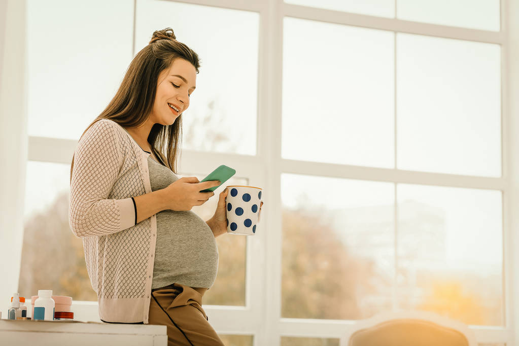 Mulher grávida bebendo chá e navegando na internet
 - Foto, Imagem