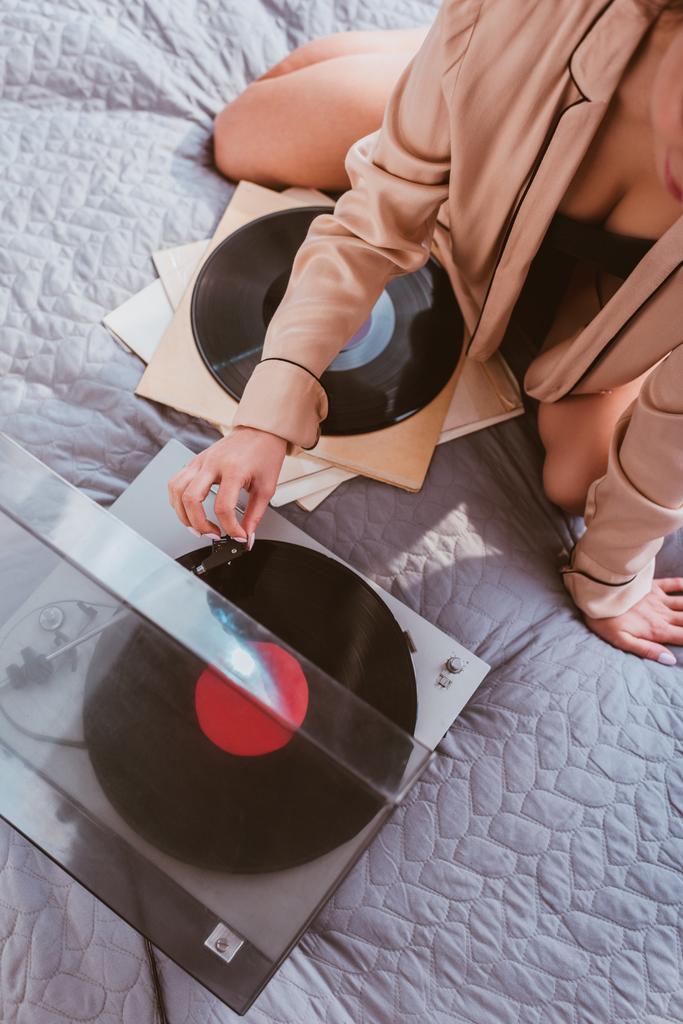 Teilbild einer jungen Frau, die zu Hause im Bett den Vinyl-Audio-Player einschaltet - Foto, Bild