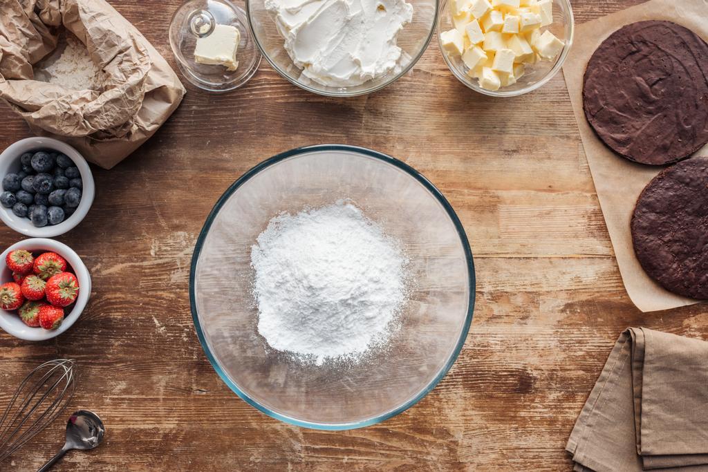Schüssel mit Mehl und Zutaten für süßen hausgemachten Kuchen auf dem Tisch  - Foto, Bild