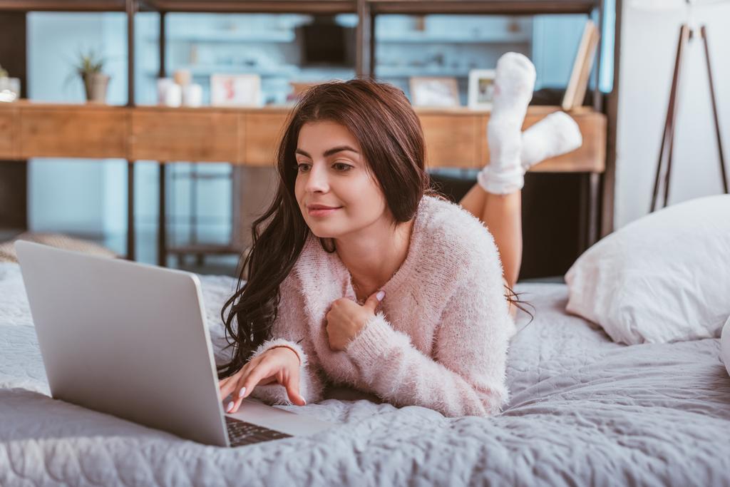 pretty female freelancer working on laptop while laying on bed at home - Fotoğraf, Görsel