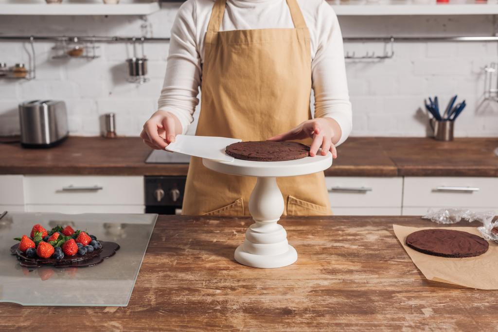 bijgesneden schot van vrouw in schort voorbereiding van heerlijke zoete taart in keuken  - Foto, afbeelding