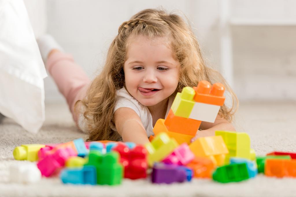rozkošný šťastně hrát s barevné plastové konstruktor na koberci u dětí pokoj - Fotografie, Obrázek