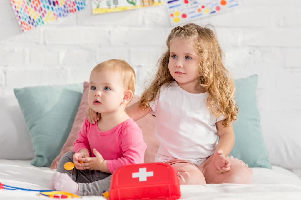 adorabili sorelle che giocano con il kit di pronto soccorso nella stanza dei bambini e distolgono lo sguardo
 - Foto, immagini