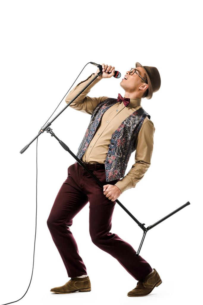 emocional elegante mestizo raza masculino músico sosteniendo micrófono y cantando aislado en blanco
 - Foto, Imagen