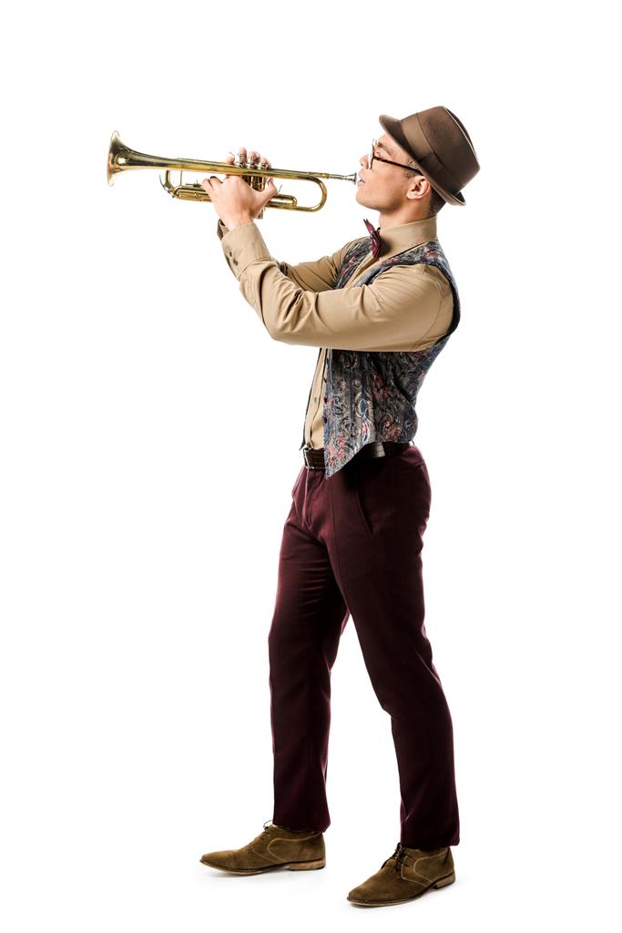 Zijaanzicht van de hipster mens in hoed en bril spelen op trompet geïsoleerd op wit  - Foto, afbeelding