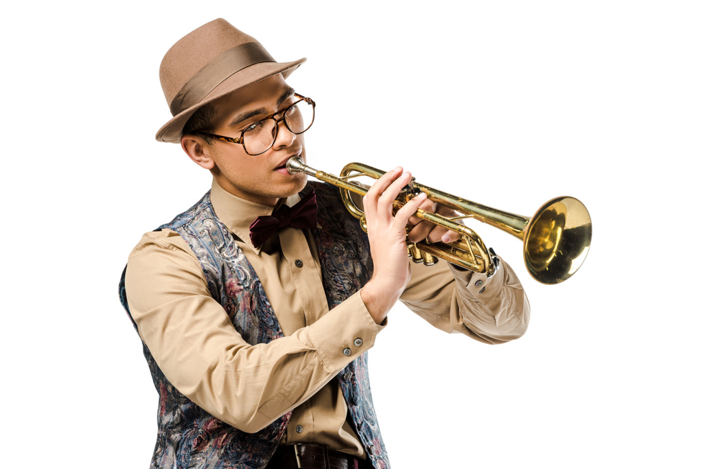 schöner, gemischter Musiker mit stylischem Hut und Brille, der auf der Trompete spielt, isoliert auf weißem Grund  - Foto, Bild