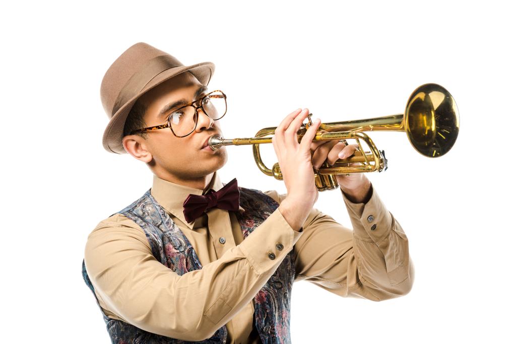 gemengd ras mannelijke zanger in stijlvolle hoed en bril spelen op trompet geïsoleerd op wit  - Foto, afbeelding