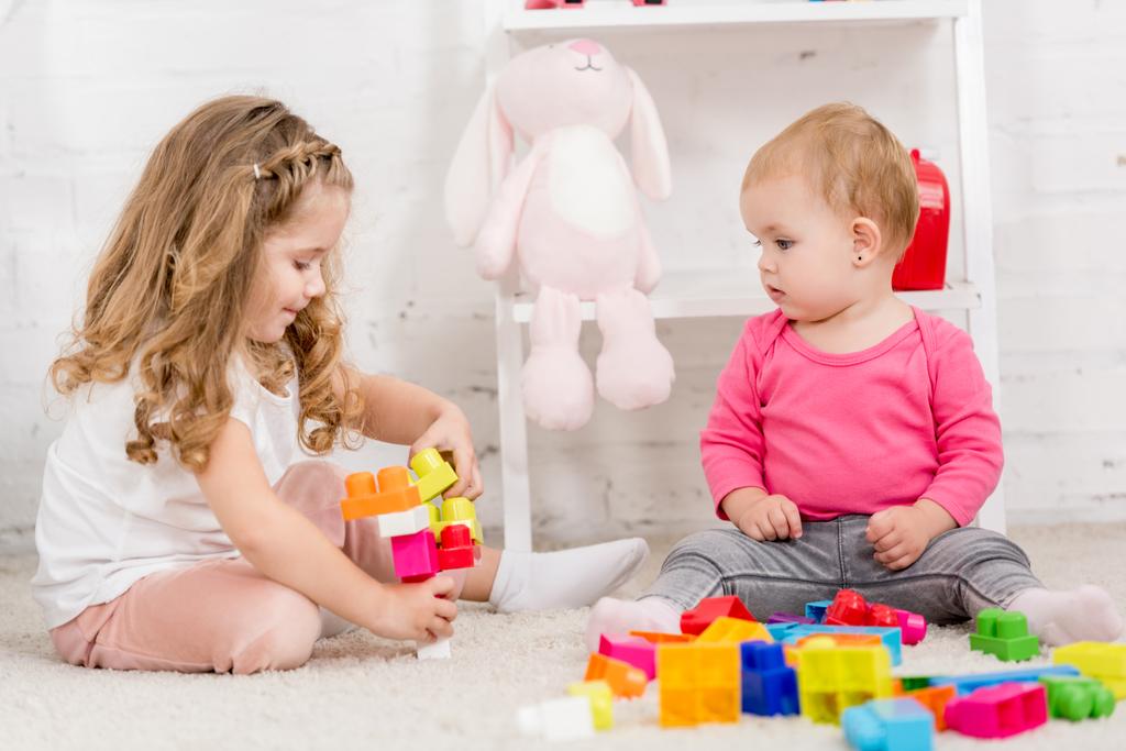 adorables sœurs jouer avec le constructeur ensemble sur le tapis dans la chambre des enfants
 - Photo, image