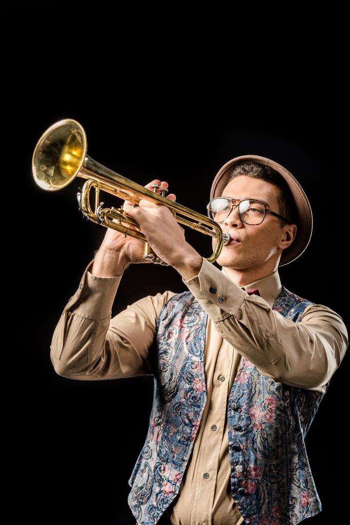 bonito masculino jazzman no chapéu e óculos tocando no trompete isolado no preto
 - Foto, Imagem
