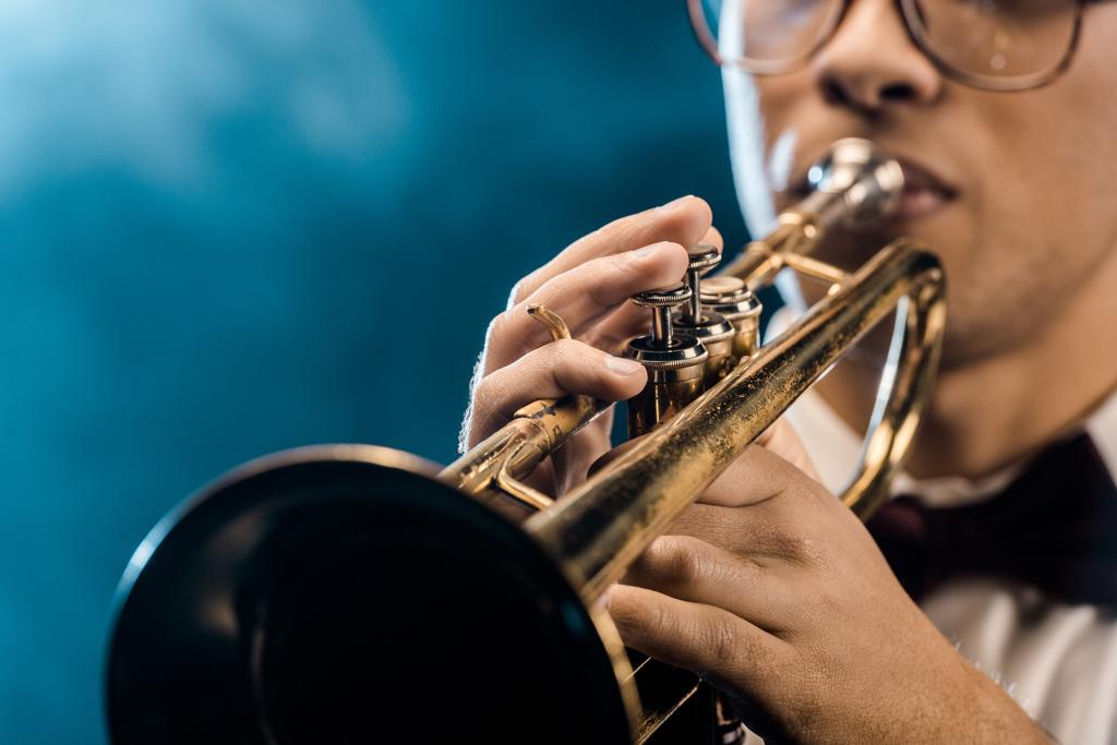 tiro recortado de músico masculino tocando trompete no palco com iluminação dramática e fumaça
 - Foto, Imagem