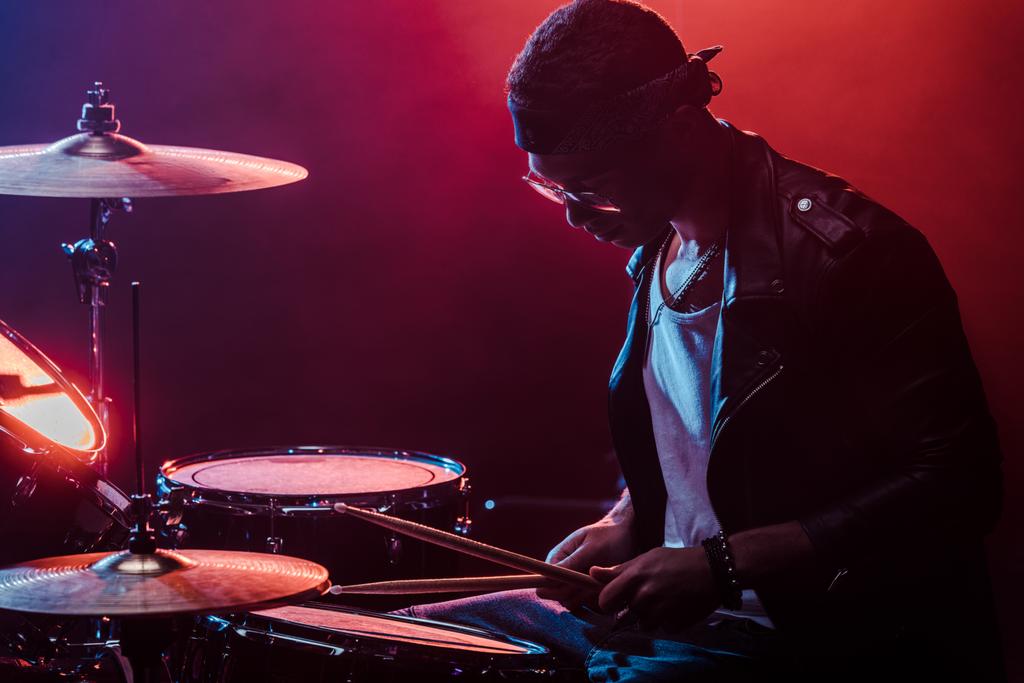 Smíšené rasy mužské hudebník v kožené bundě, hraje na bicí během rockový koncert na jevišti   - Fotografie, Obrázek