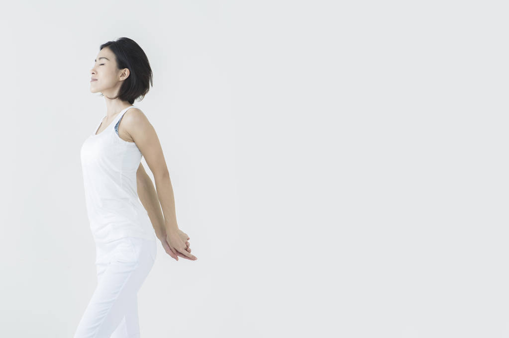 Νεαρή γυναίκα της Ασίας τα χέρια πίσω από το σώμα της και την άσκηση - Φωτογραφία, εικόνα