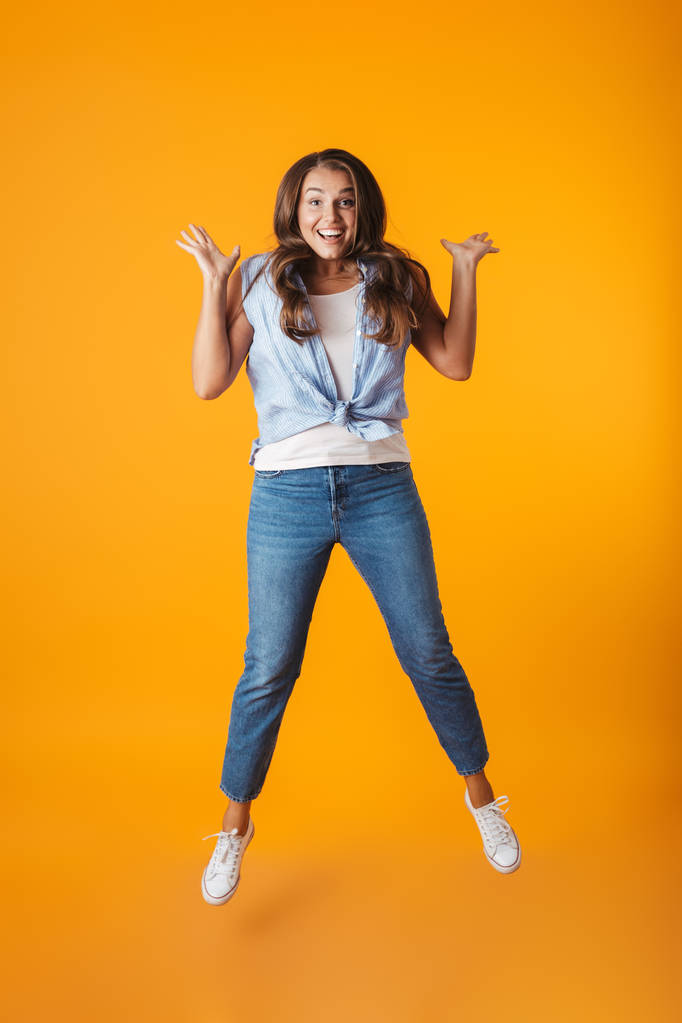 Portret van de volledige lengte van een enthousiast jong casual vrouw springen geïsoleerd op gele achtergrond, vieren van succes - Foto, afbeelding