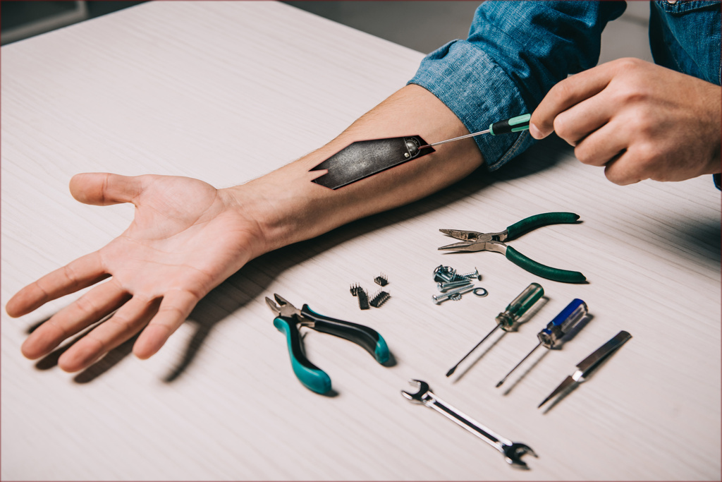 Ausgeschnittene Ansicht eines Mannes, der einen metallischen Mechanismus im Arm mit Werkzeugen repariert - Foto, Bild