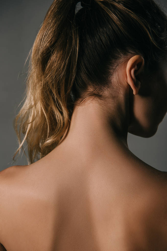 back view of blonde woman with ponytail on grey background - Photo, Image