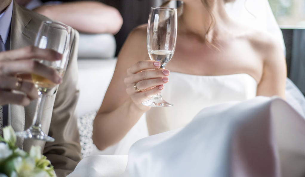 Tema y estilo de la boda. Las novias y las manos del novio se mantienen juntas con un hermoso y elegante ramo de rosas blancas y copas de champán.
. - Foto, imagen