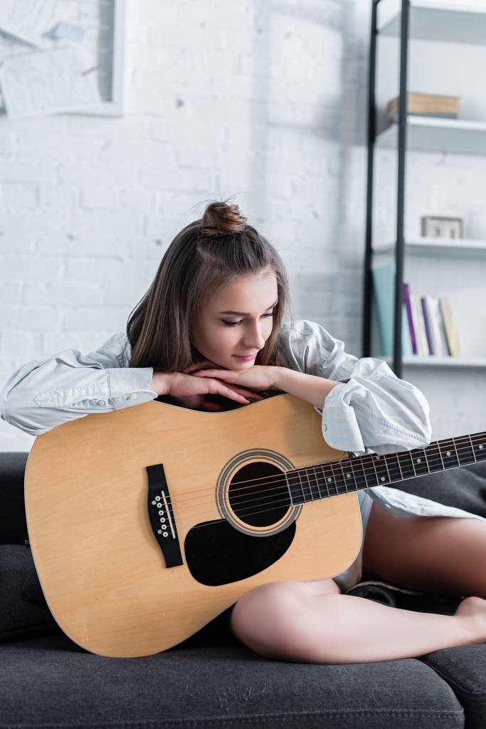 promyšlené hudebník seděl na pohovce a doma drží akustická kytara - Fotografie, Obrázek
