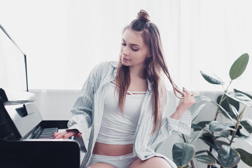 Sexy Musikerin in Hemd und Unterwäsche spielt Klavier im Wohnzimmer - Foto, Bild