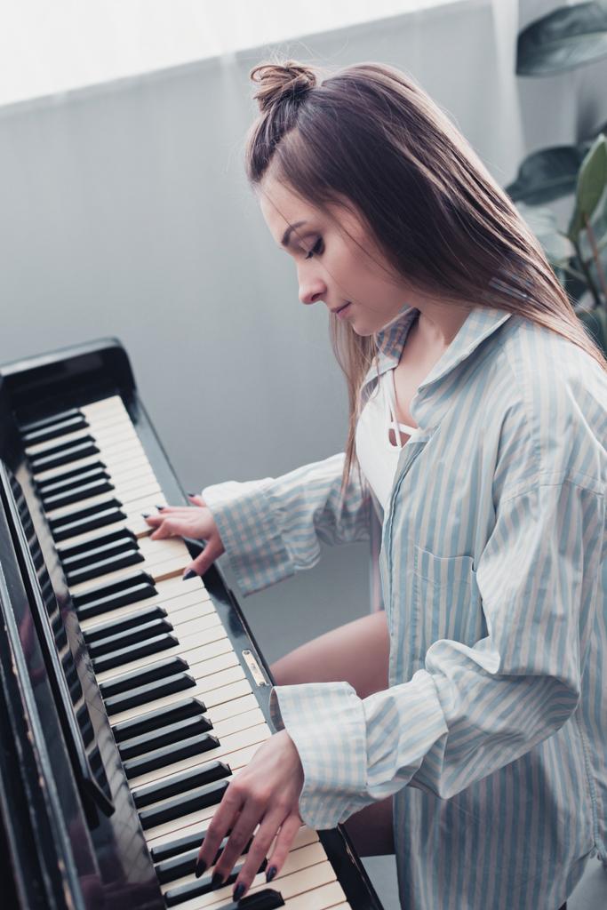 attractive musician playing piano in living room - Photo, Image