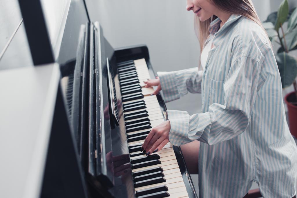 обрізаний подання музикант грав на фортепіано і усміхнений у вітальні - Фото, зображення