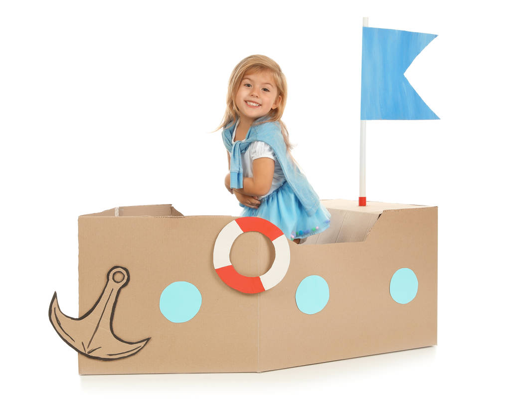 Χαριτωμένο μικρό κορίτσι παίζει με χαρτόνι πλοίο σε λευκό φόντο - Φωτογραφία, εικόνα