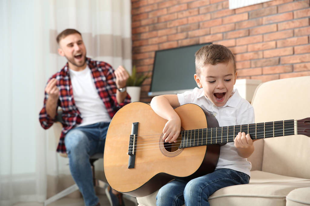 Pai e filho tocando guitarra e cantando em casa
 - Foto, Imagem