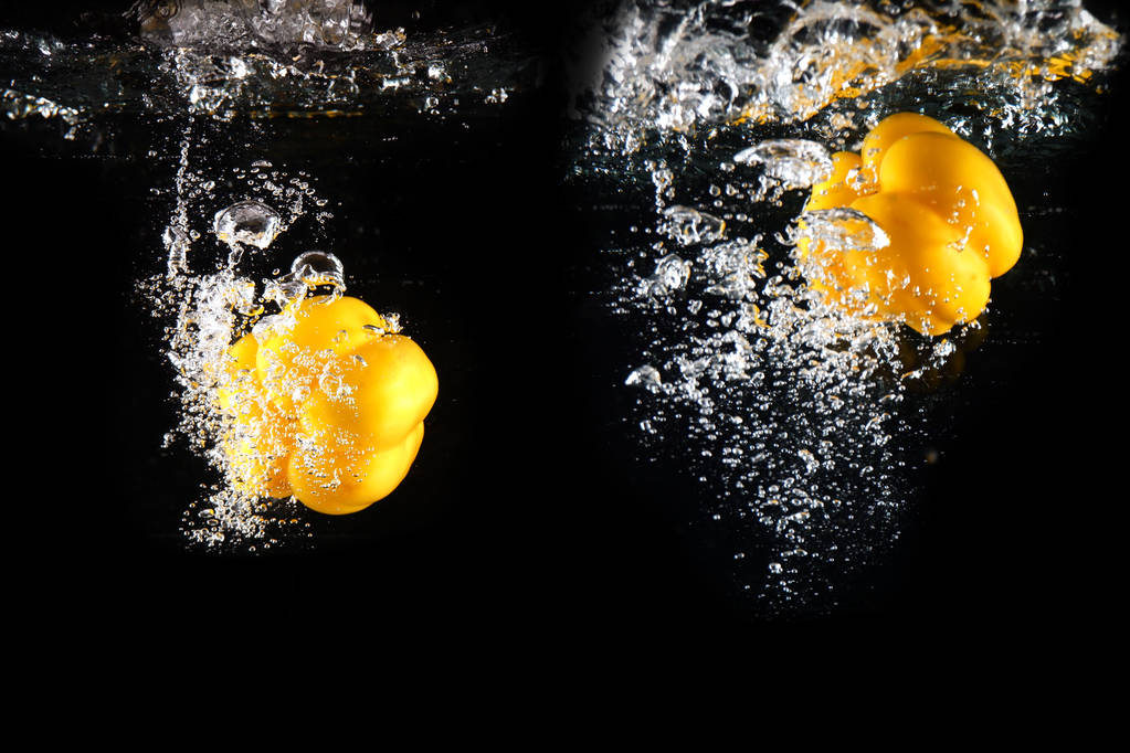 Poivron jaune frais avec éclaboussure d'eau et bulle isolée. Espace de copie. Paprika jaune juteux tombé dans l'eau sur fond noir idéal pour toute utilisation
. - Photo, image