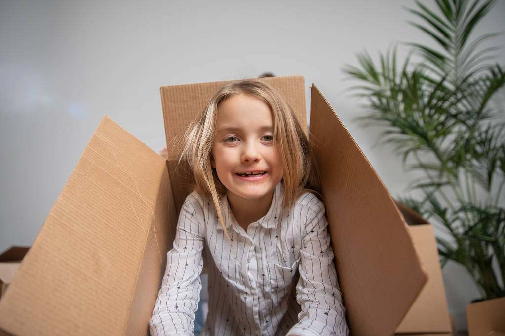 Фото счастливой девушки, выглядывающей из картонной коробки
 - Фото, изображение