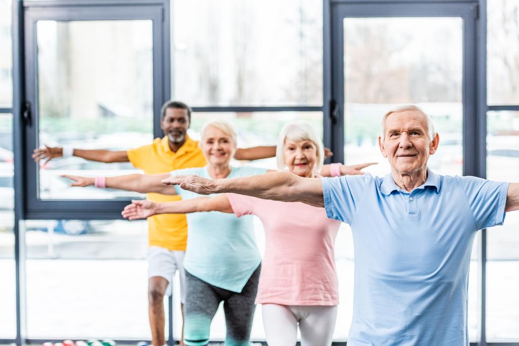 Multikulti-Senioren-Athleten synchron beim Turnen im Fitnessstudio - Foto, Bild