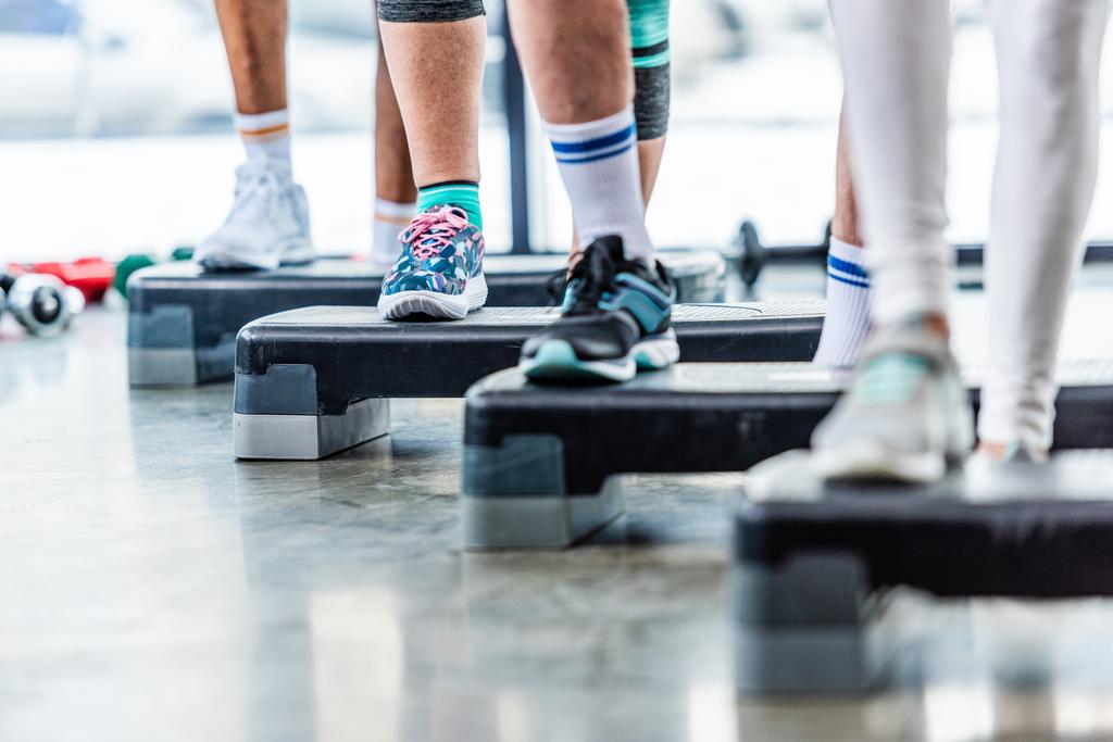 vista parcial de deportistas haciendo ejercicio en plataformas escalonadas en el gimnasio
 - Foto, imagen